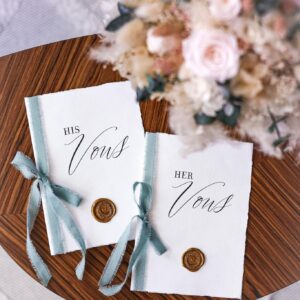 Beautifully styled his and her vow books with a floral bouquet on a wooden table, perfect for weddings.