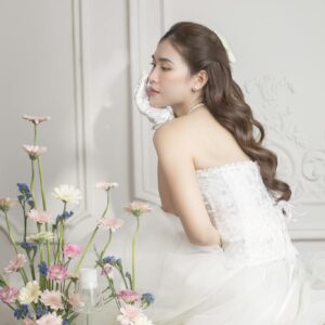 Elegant bride poses gracefully in a vintage setting with vibrant floral arrangement and classic wedding decor.