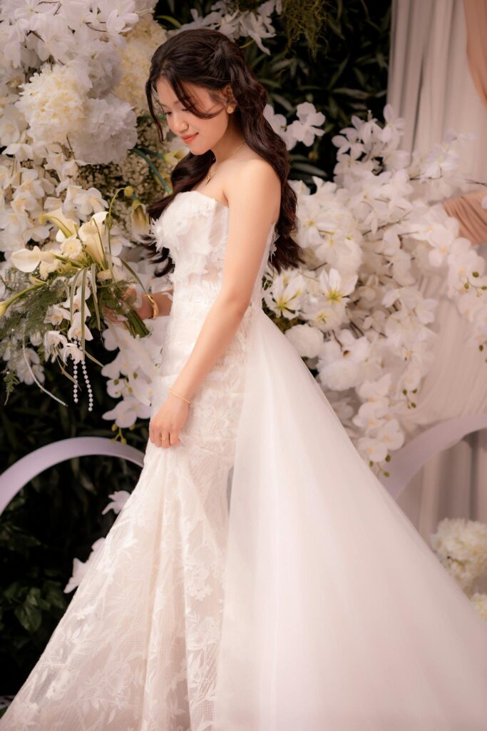 Beautiful Asian bride in a floral wedding setting wearing an elegant lace dress.