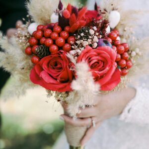 Close-up of a bridal bouquet with red roses and berries, perfect for weddings.