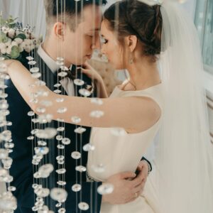 Photo by Irina Iriser Elegant bride and groom embrace amidst sparkling crystal decor in a romantic indoor setting.