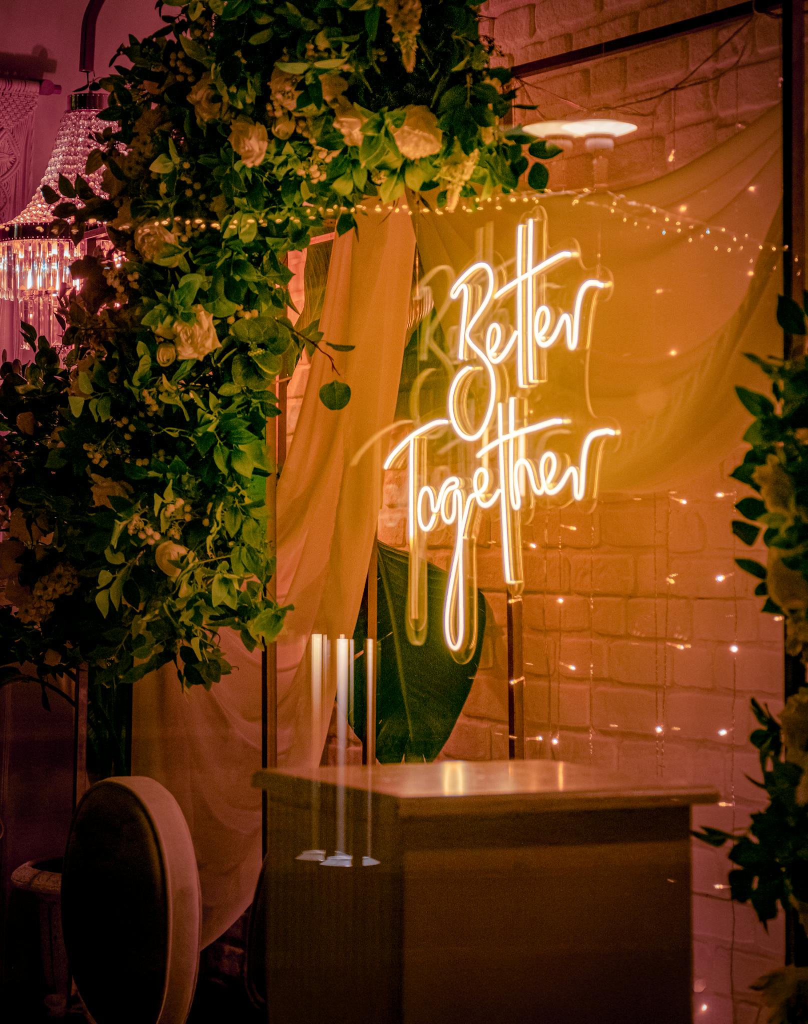Stylish indoor wedding scene with neon 'Better Together' sign and lush floral decorations, perfect for modern ceremonies.