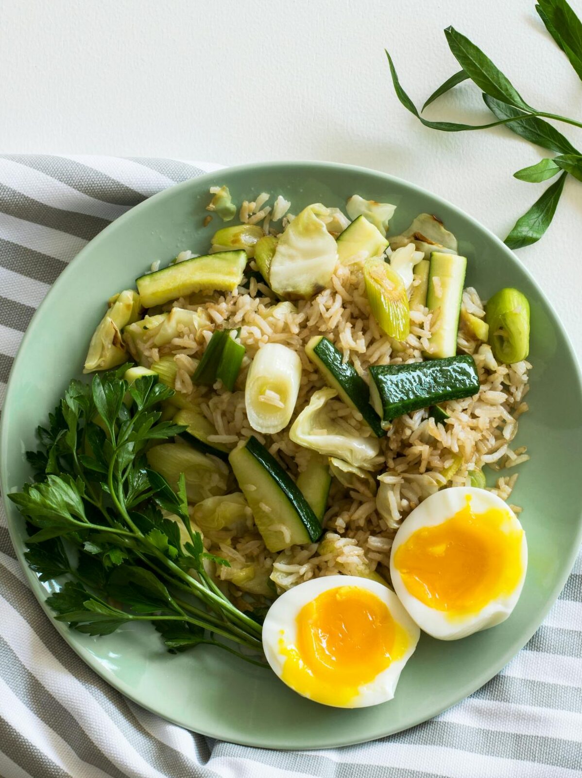 Rice With Zucchini, Soft Boiled Egg, and Parsley in Green Ceramic Plate