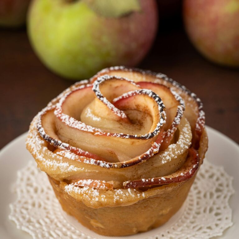 A beautifully crafted apple rose tart on a ceramic plate, perfect for dessert delights.