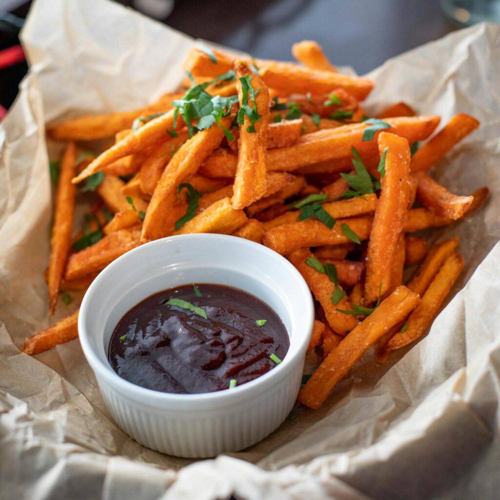 Appetizing sweet potato fries served with a rich dipping sauce, garnished with fresh herbs.