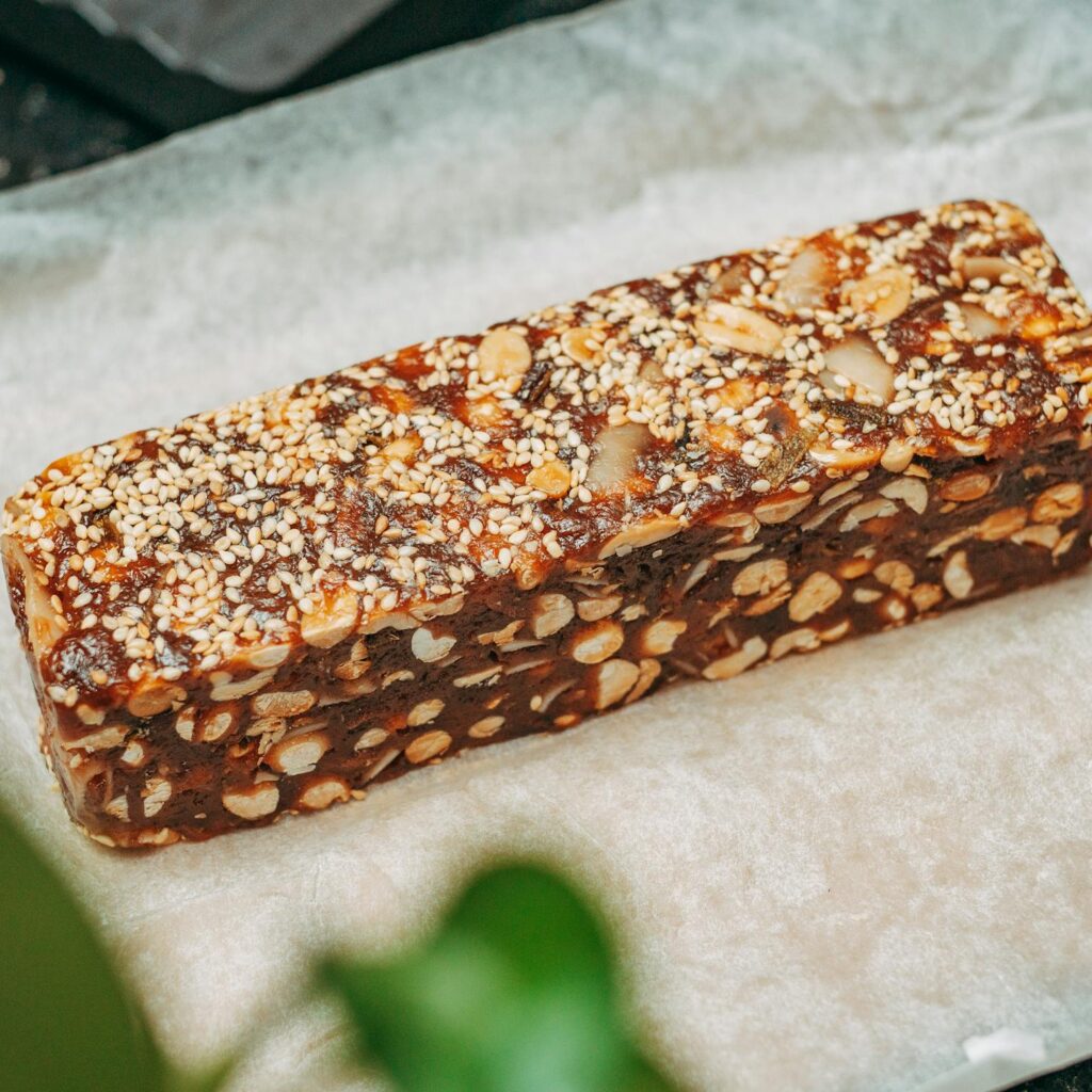 Close-up image of a nut and sesame seed protein bar on parchment paper, ideal for healthy snacking.