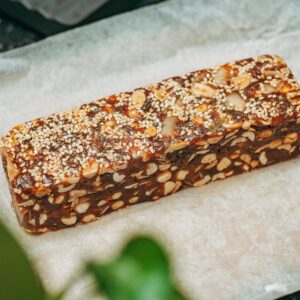 Close-up image of a nut and sesame seed protein bar on parchment paper, ideal for healthy snacking.