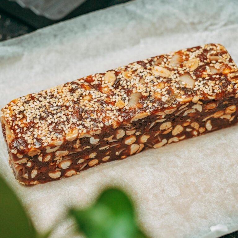 Close-up image of a nut and sesame seed protein bar on parchment paper, ideal for healthy snacking.