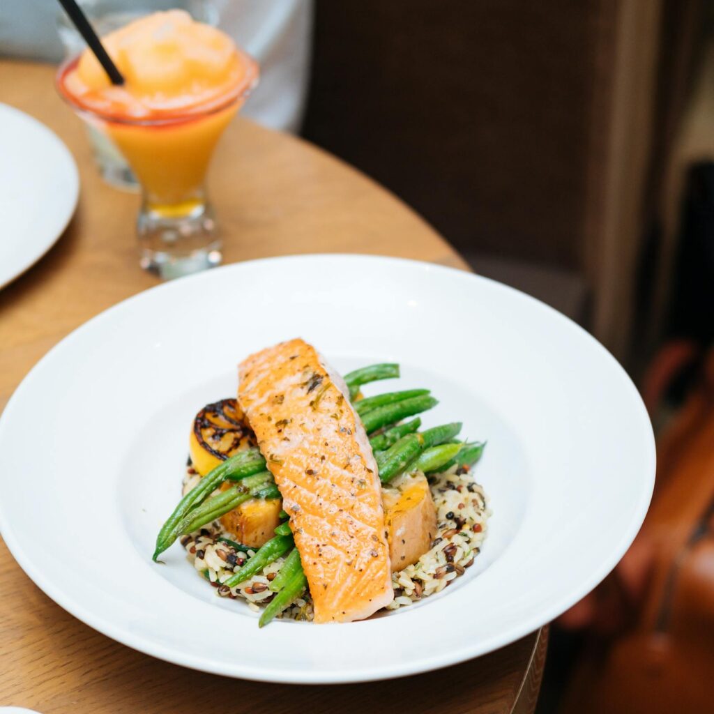 Grilled salmon served with quinoa, asparagus, and squash on a round table setting.