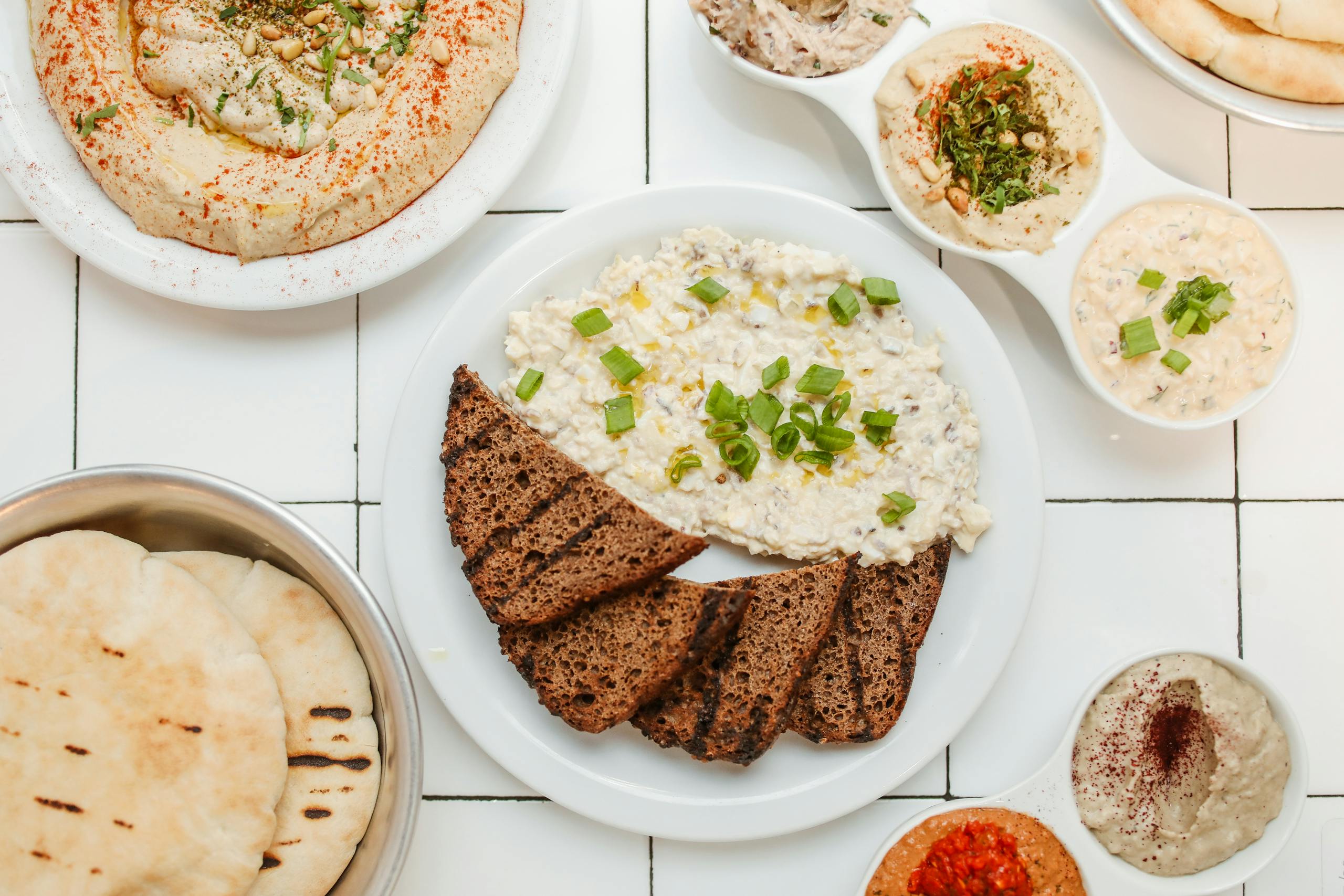Top view of Mediterranean dips with rye bread, showcasing variety and delicious presentation.