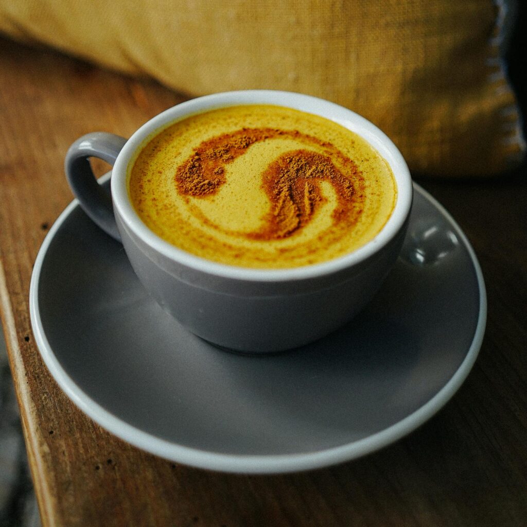 Warm turmeric latte with cinnamon froth art, served in a cozy indoor setting.