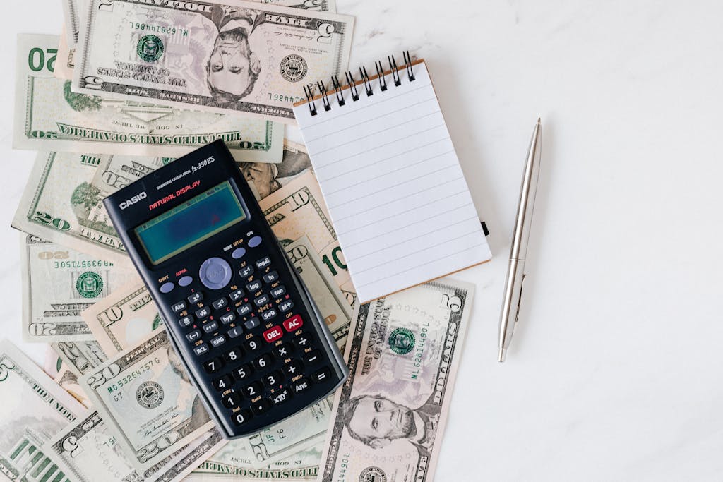 Flat lay of US dollar bills with calculator and notebook for budgeting. Photo By: Kaboompics.com