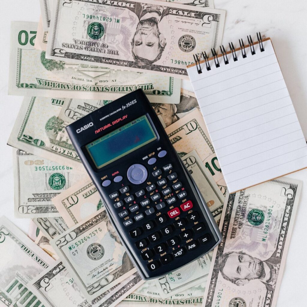 Flat lay of US dollar bills with calculator and notebook for budgeting. Photo By: Kaboompics.com