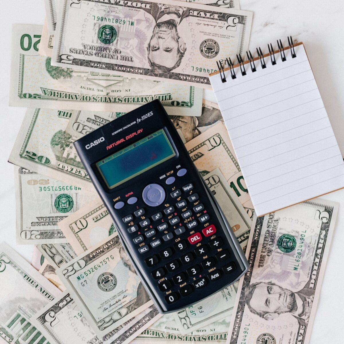 Flat lay of US dollar bills with calculator and notebook for budgeting. Photo By: Kaboompics.com