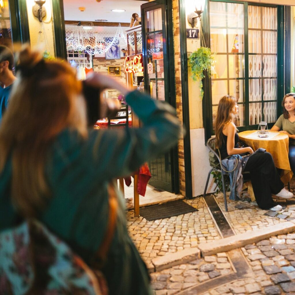 Outdoor café scene with people enjoying a lively evening on a cobblestone street.