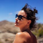 Portrait of a woman with sunglasses enjoying the sunlight in a scenic outdoor Spanish landscape.