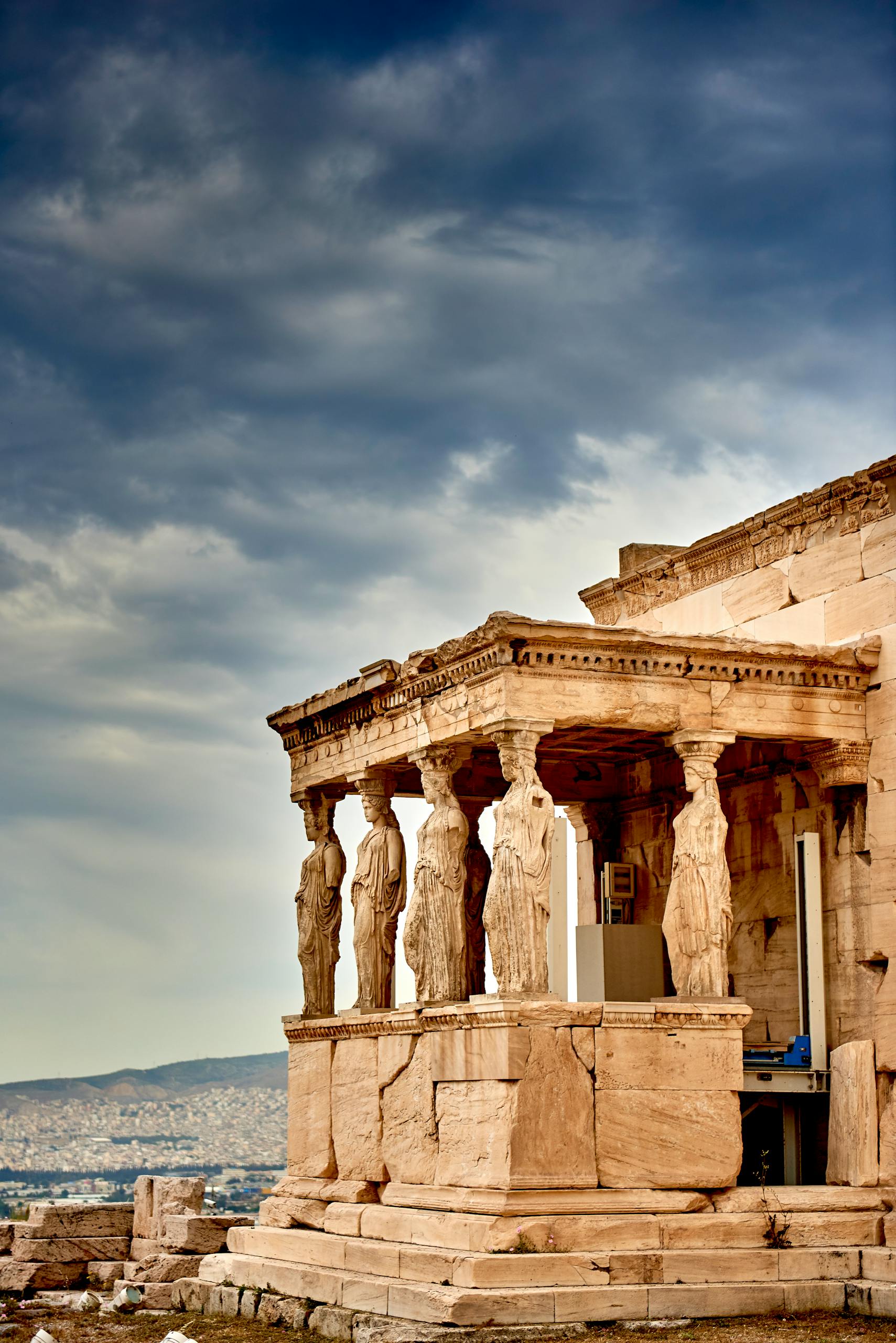 View of the Erechtheion Temple's Caryatids on the Acropolis in Athens, Greece, against a dramatic sky.