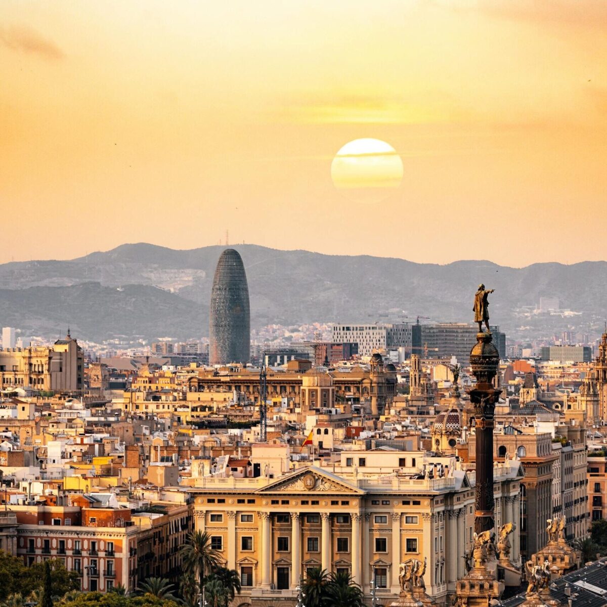 A stunning sunset view of the Barcelona skyline showcasing iconic landmarks and a warm, golden hour glow.