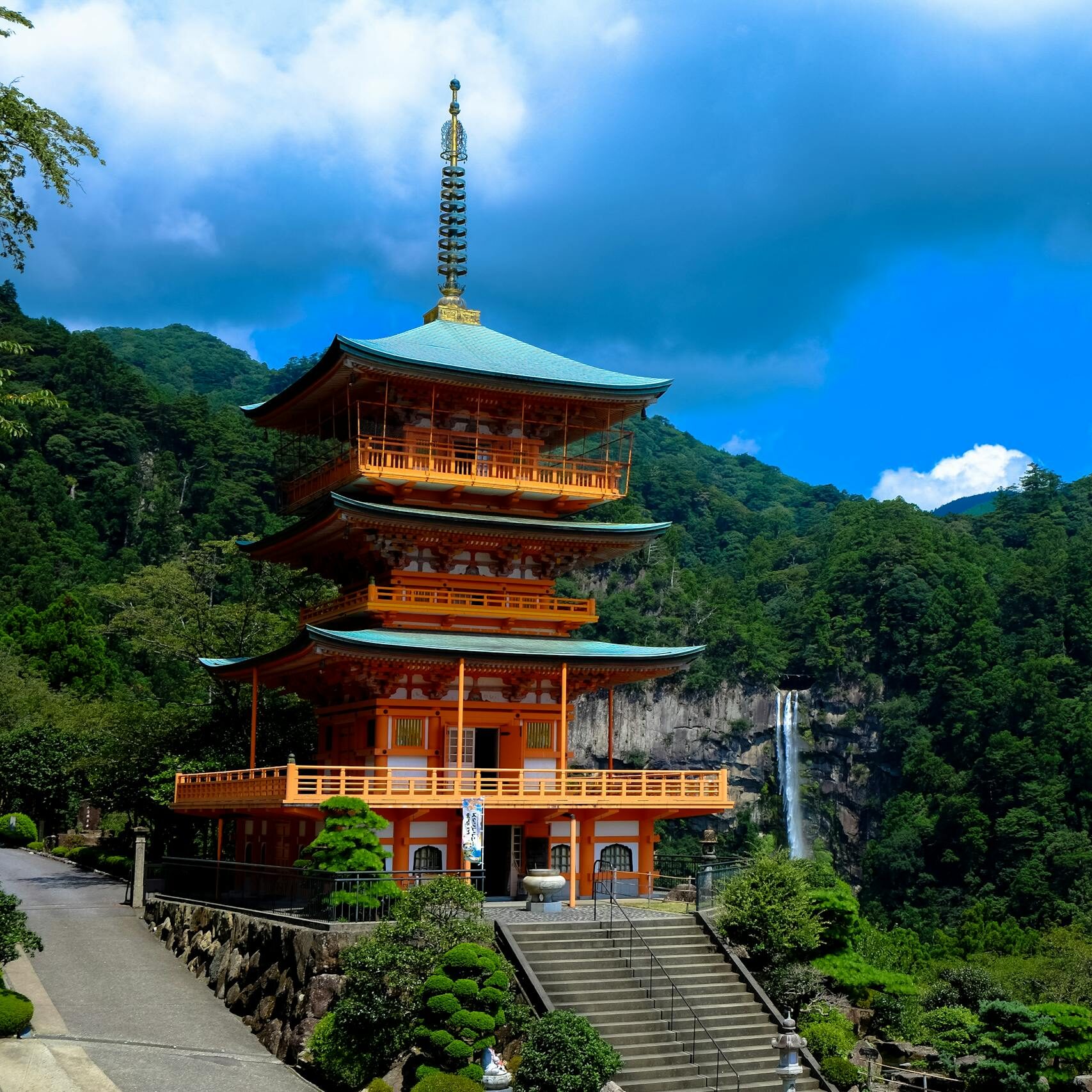 Beautiful view of Kumano Nachi Taisha with a pagoda surrounded by lush green mountains and a waterfall.