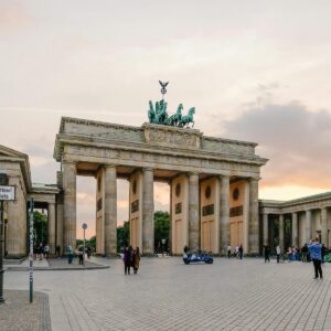 Scenic view of Berlin's Brandenburg Gate with people gathering at sunset.