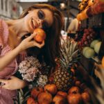 Young woman enjoying a moment with fresh fruits at an outdoor Turkish market, holding a pomegranate,