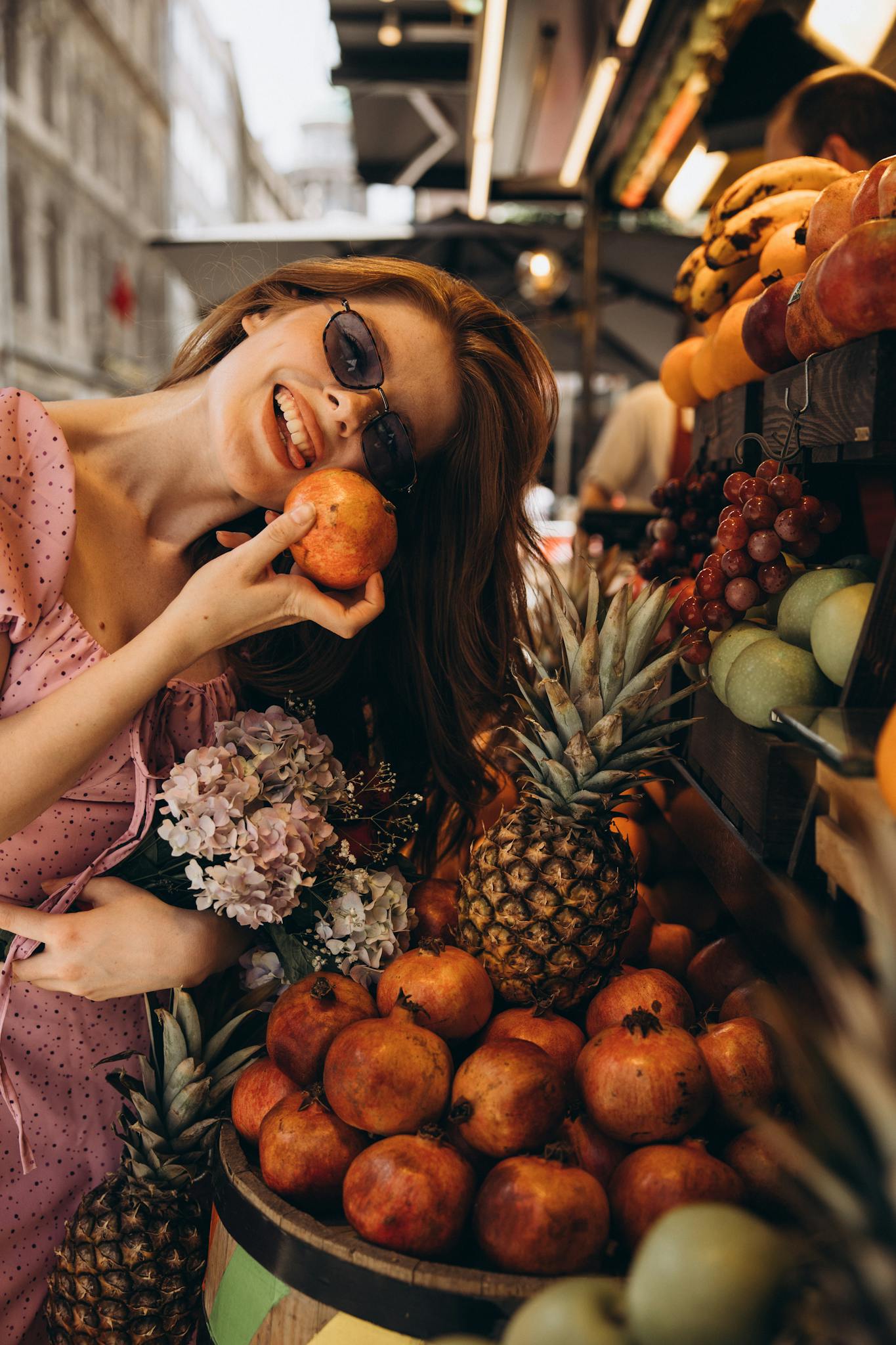 Young woman enjoying a moment with fresh fruits at an outdoor Turkish market, holding a pomegranate,
