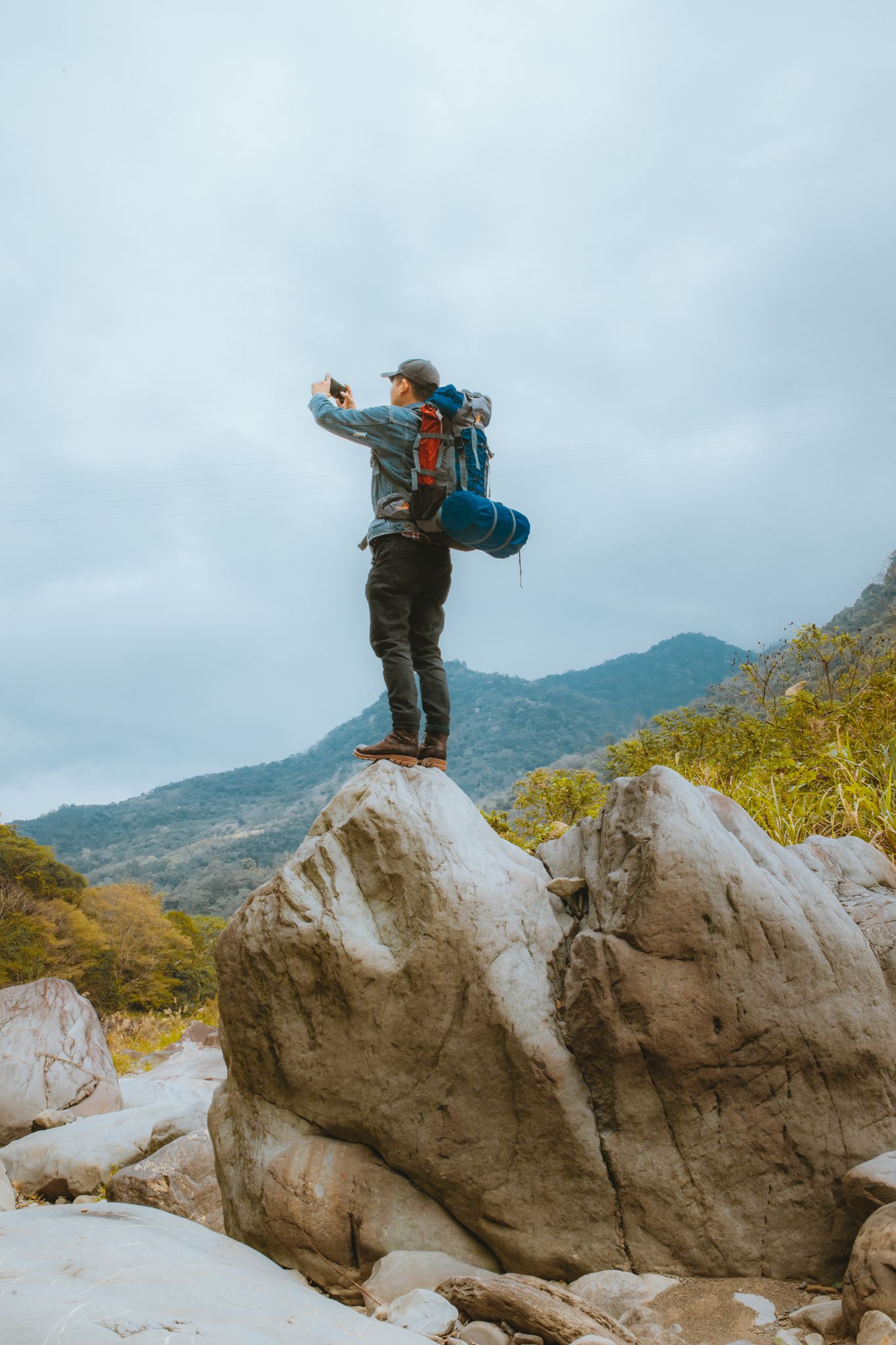 A lone backpacker capturing the stunning mountain landscape from atop a rock.