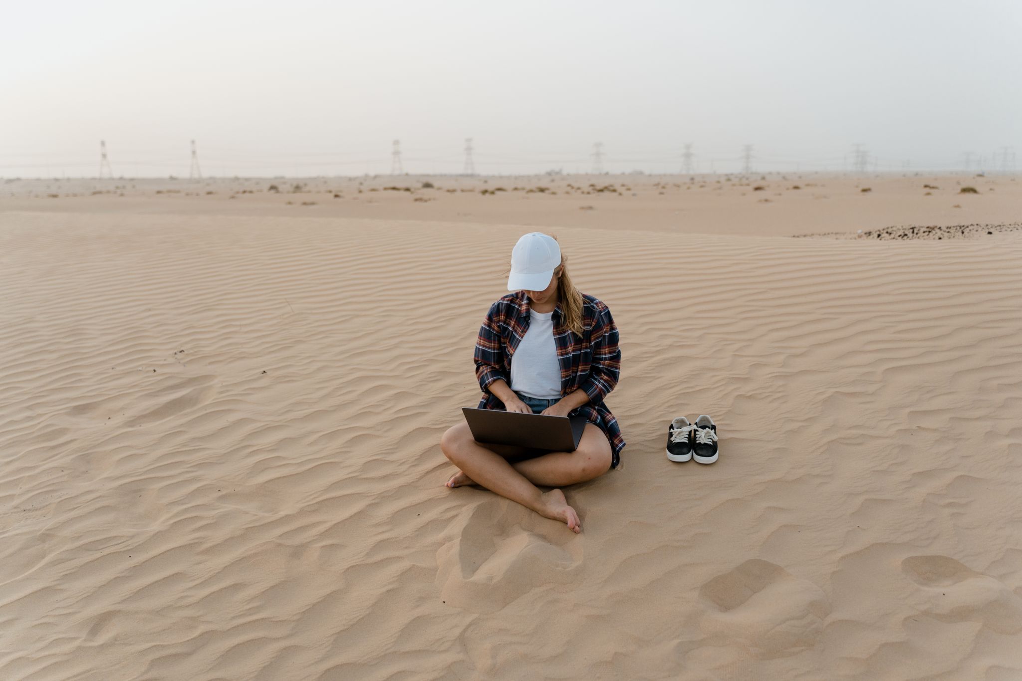 A woman in a desert using a laptop, symbolizing remote work freedom and digital nomad lifestyle.