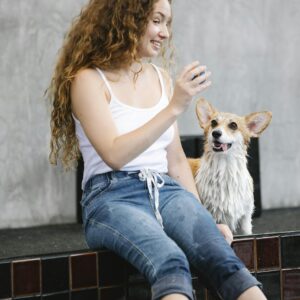 Young woman playing with her Pembroke Welsh Corgi dog inside a modern setting.