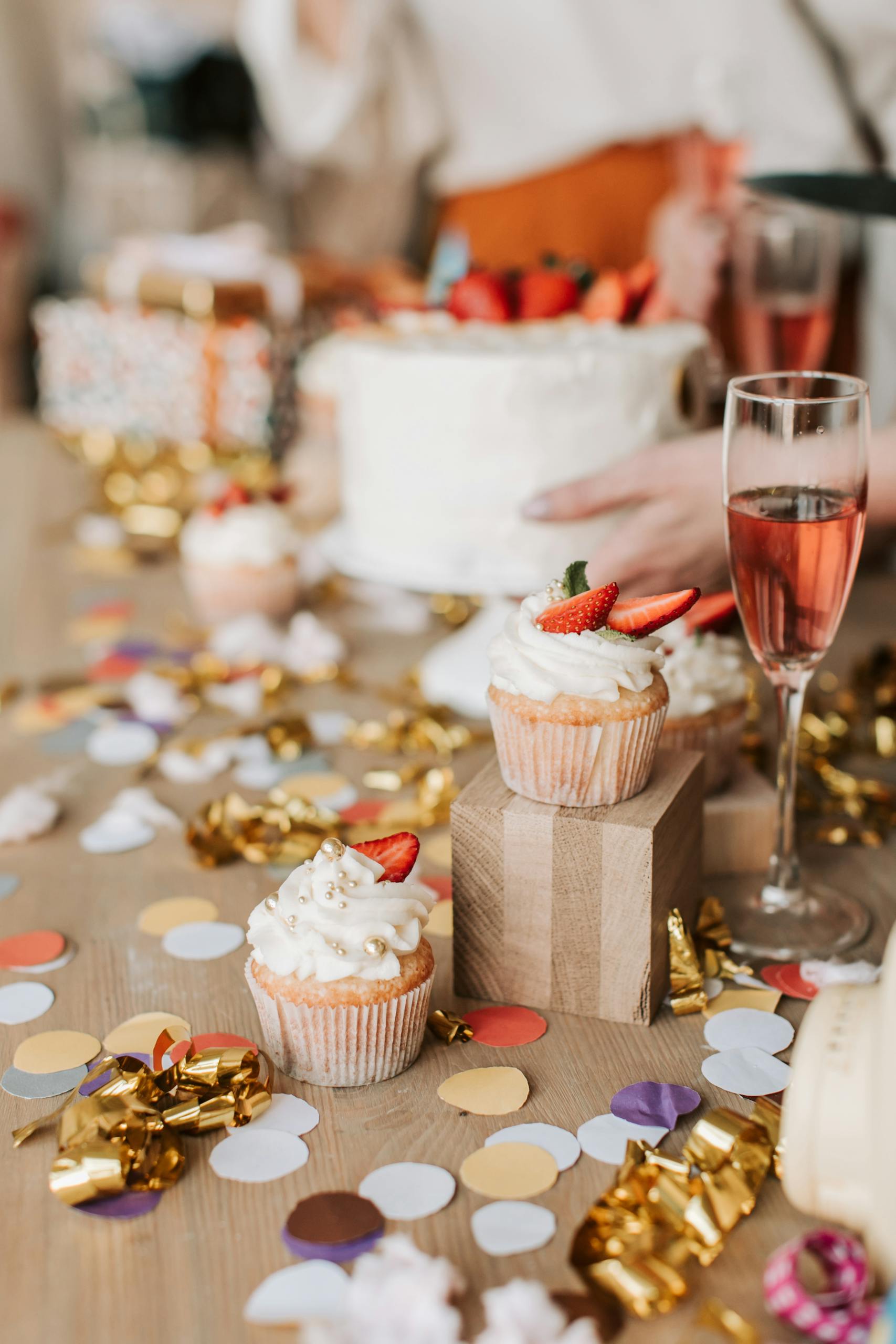 A vibrant party scene with cupcakes, a cake, and champagne on a confetti-strewn table.