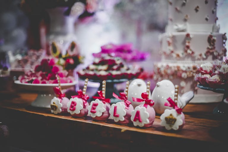 Charming dessert table setup featuring personalized cake pops and a tiered cake, perfect for celebrations.