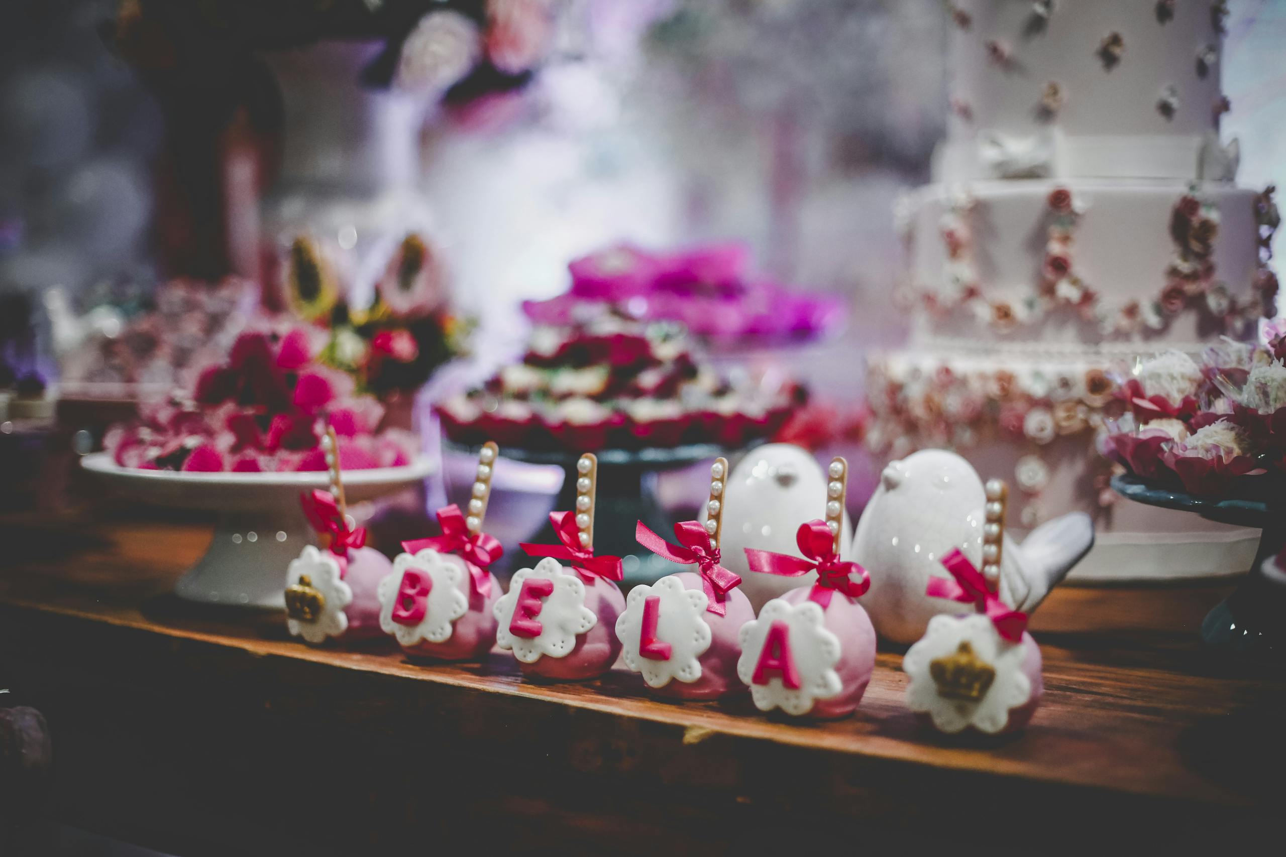 Charming dessert table setup featuring personalized cake pops and a tiered cake, perfect for celebrations.