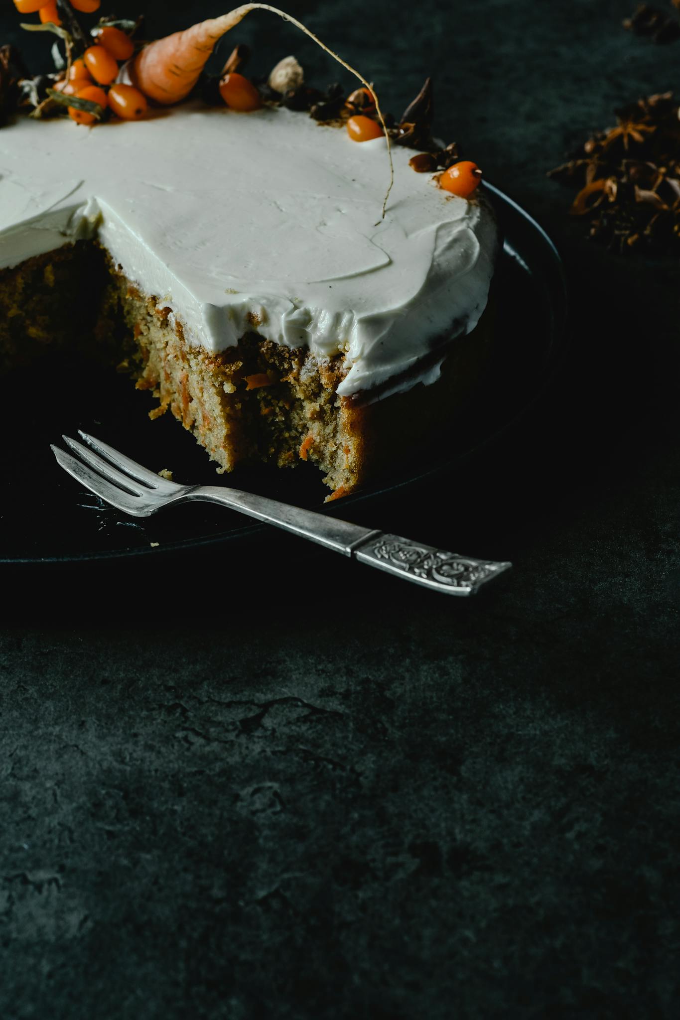 Close-up of a carrot cake slice topped with cream cheese frosting, perfect for dessert lovers.