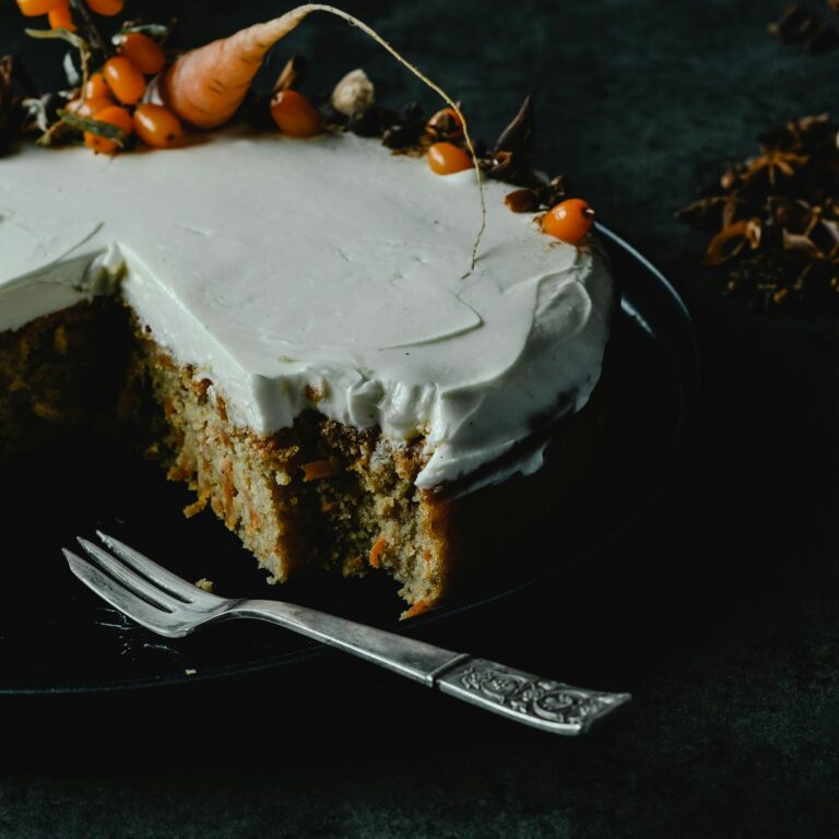 Close-up of a carrot cake slice topped with cream cheese frosting, perfect for dessert lovers.