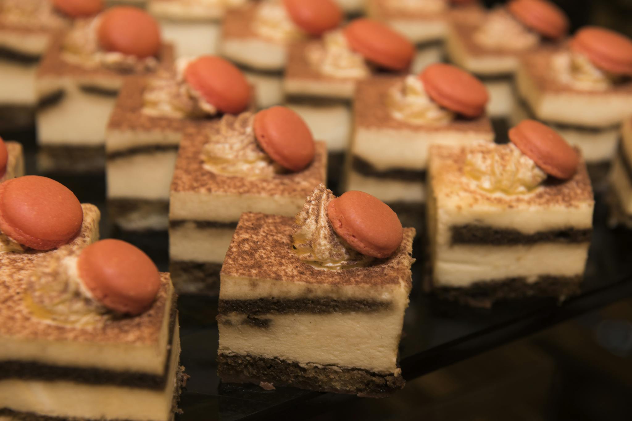 Close-up of tiramisu slices topped with macarons, perfect for a sweet treat display.