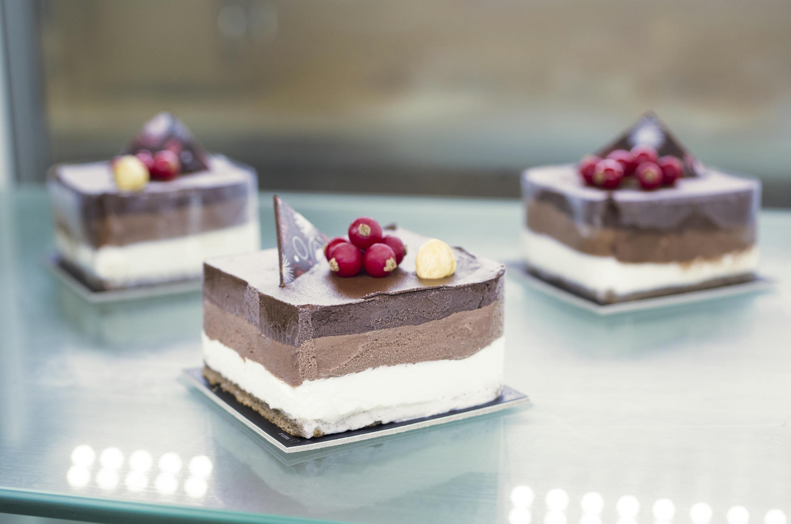 Delicious chocolate mousse cakes with berries and nuts on a glass surface.