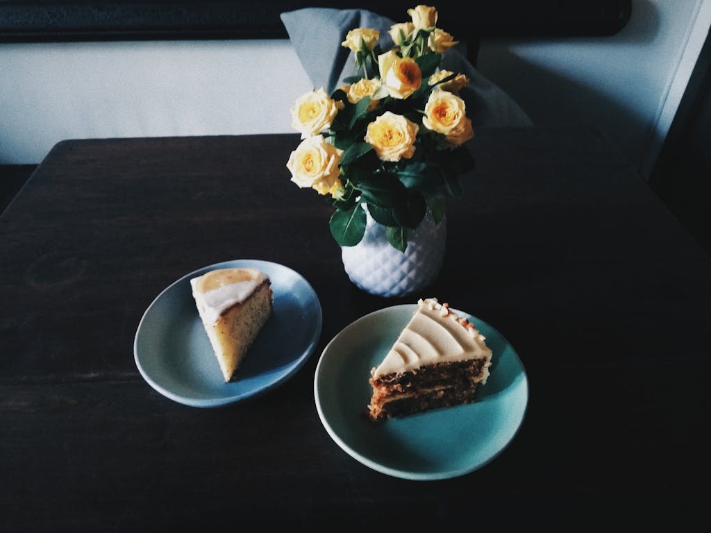 Indulgent slices of cake accompanied by a bouquet of yellow roses in a cozy indoor setting.