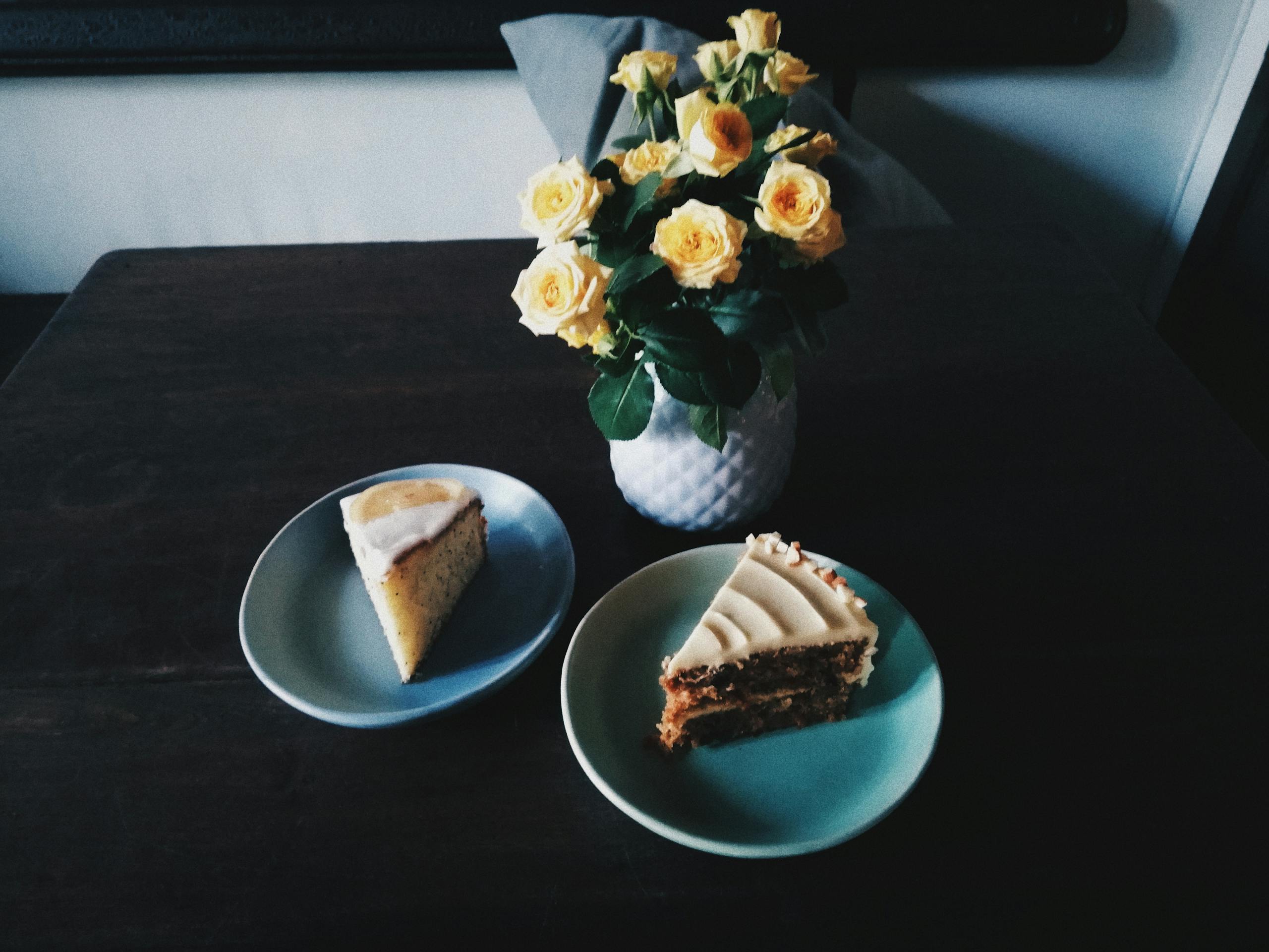 Indulgent slices of cake accompanied by a bouquet of yellow roses in a cozy indoor setting.