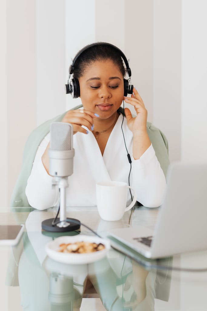 A woman enjoys podcasting at home with a microphone and headphones, embracing technology.