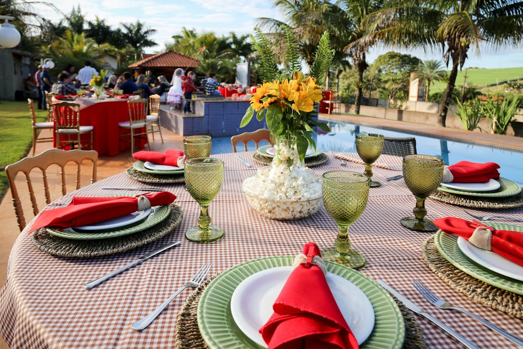 Vibrant outdoor dining setup with floral centerpiece by a pool, perfect for social gatherings.