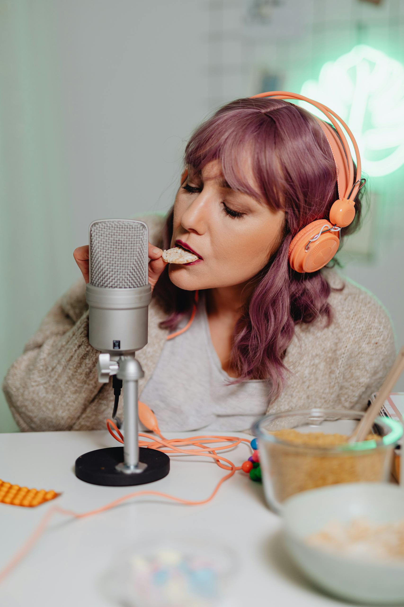Woman creating ASMR content with microphone and headphones in a studio setting.