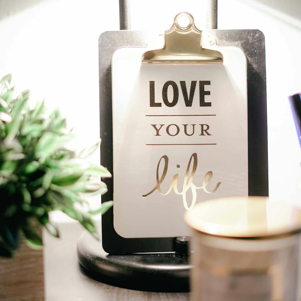 A warmly lit desk setup featuring a lamp, inspirational clipboard, and decor for a cozy ambiance.