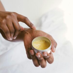 Close-up of a hand applying natural skincare cream, emphasizing self-care and holistic health.