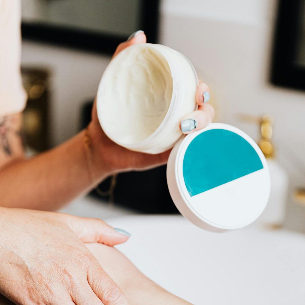 Close-up of a woman using lotion on her leg for skin care with manicured nails.