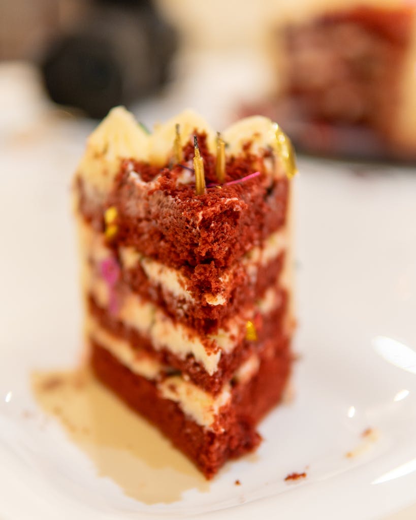 Delicious red velvet cake slice on a white plate with creamy frosting.