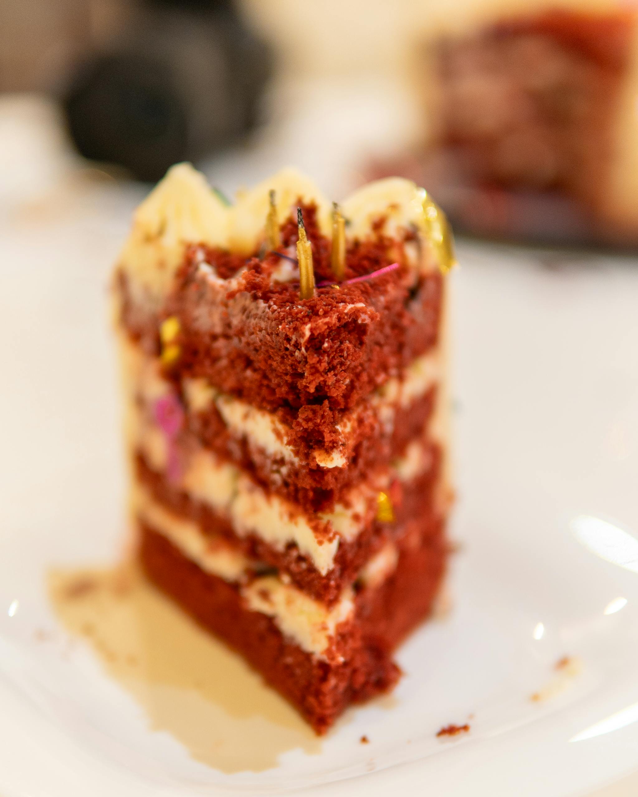 Delicious red velvet cake slice on a white plate with creamy frosting.