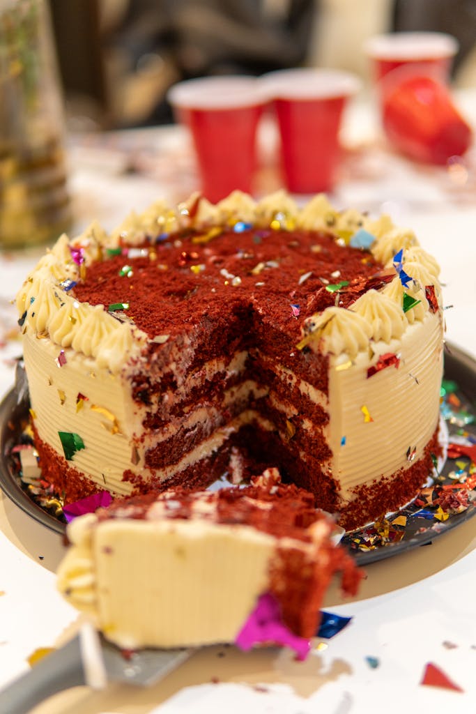 Delicious red velvet cake with cream cheese frosting and confetti, perfect for parties.