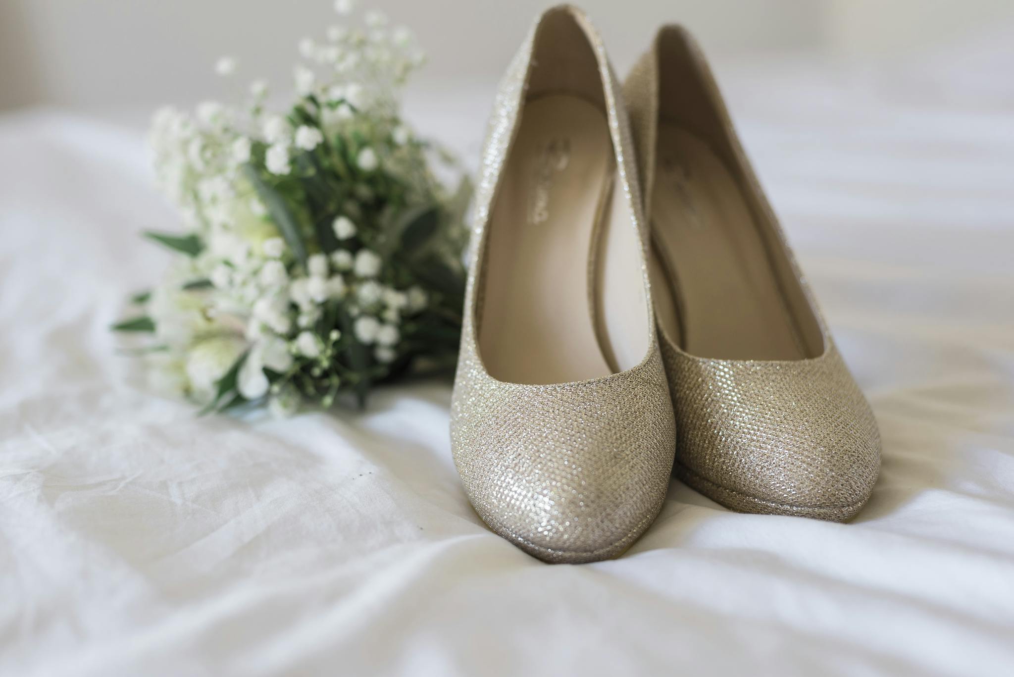 Beautiful golden bridal shoes paired with a delicate white bouquet, perfect for wedding style inspiration.